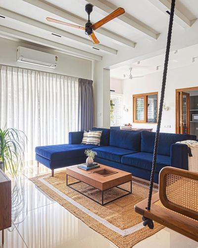 Living room with navy sectional sofa, wooden coffee table on jute rug, and hanging cane swing chair