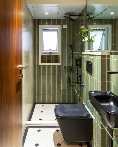 Small bathroom with green tiled walls, black fixtures and patterned marble-look floor