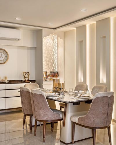 Beige dining room with marble table, upholstered chairs, and a backlit carved jali screen