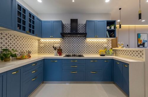 U-shaped kitchen with blue shaker cabinets, patterned backsplash, and black chimney hood