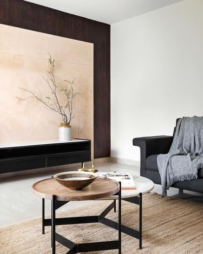 Minimalist living room with stone feature wall, fluted wood panelling, round wood coffee table and charcoal sofa