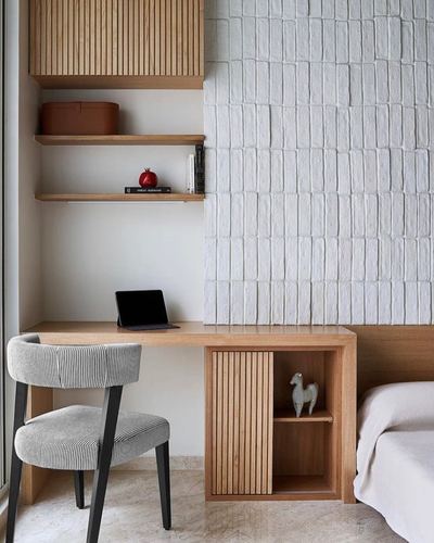 Wood desk with striped chair beside textured white plaster wall and shelving in bedroom nook
