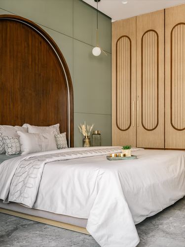 Bedroom with arched wood headboard, sage green paneling, and fluted wardrobe doors
