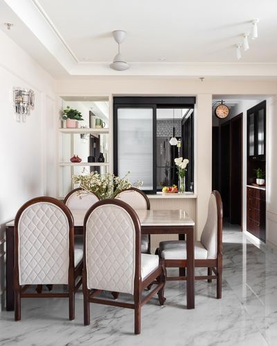 Dining room with marble table, dark wood arched chairs, and open display shelving beside a window