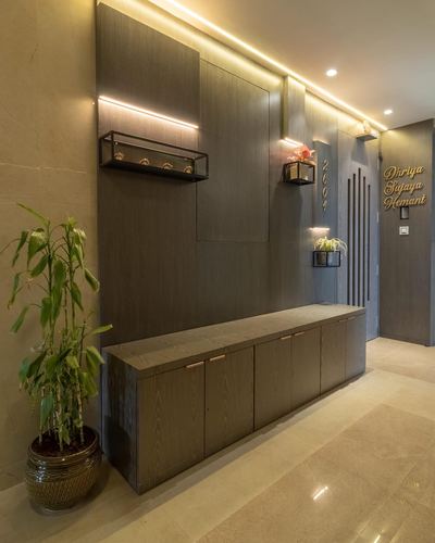 Entryway with dark wood paneled wall, cove lighting, console cabinet and potted plant near door