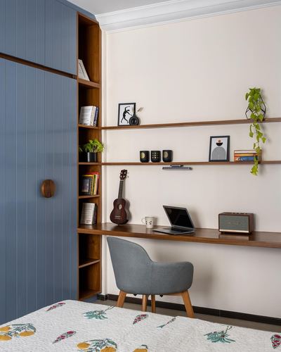 Study nook with wooden floating desk, open shelves, blue wardrobe and grey chair