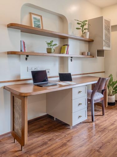 Home office nook with wood desk, floating shelves in curved niche, laptop and tablet on top