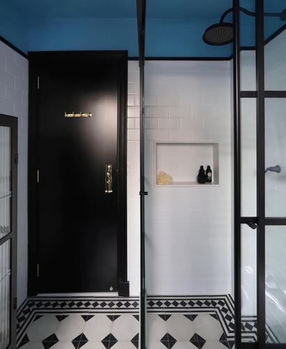 Black door and white subway tile bathroom with black-framed glass shower partition and patterned floor