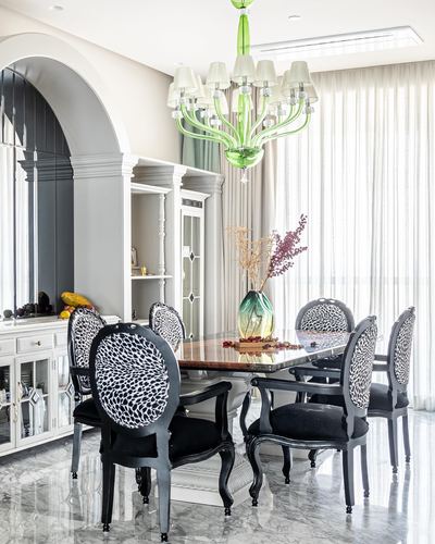 Formal dining room with green glass chandelier, patterned chairs, marble floor and arched niche