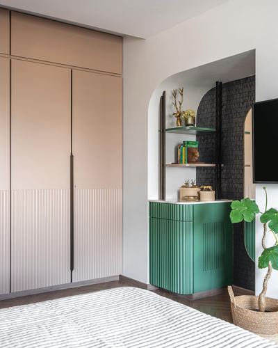 Bedroom corner with pink fluted wardrobe and green fluted cabinet in arched niche with shelving
