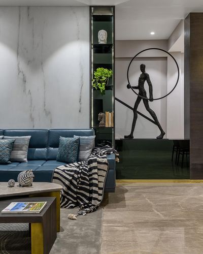 Living room with blue leather sofa, marble wall, and bronze figure-with-hoop sculpture beyond