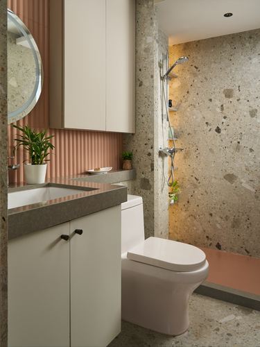 Small bathroom with terracotta accents, terrazzo walls, white vanity, and open shower area