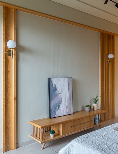 Bedroom wall with oak-framed sage panel, wall sconces, and a wooden console table with artwork.