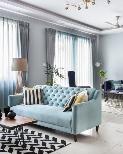 Powder blue tufted sofa on black and white chevron rug in bright living room
