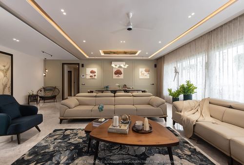 Neutral-toned living room with sectional sofa, wooden coffee table, dark rug and cove-lit ceiling