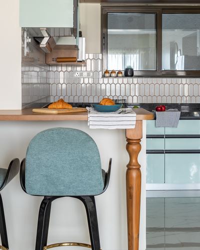 Kitchen counter with arched tile backsplash, turned wood leg, and teal bar stool