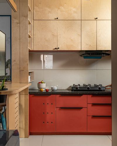Small kitchen with plywood upper cabinets, red lower cabinets, black countertop, gas stove and chimney