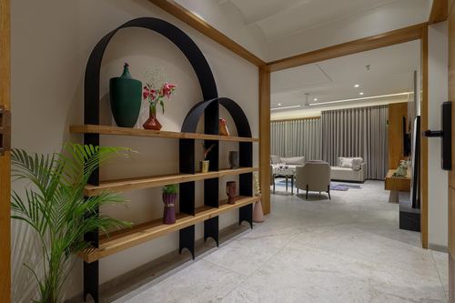 Hallway with arched black shelving holding vases, leading into a lit living room beyond