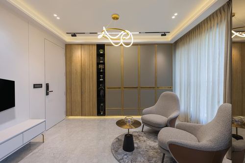 Living room with grey-gold panelled wardrobe, boucle armchairs, marble table and sculptural pendant light