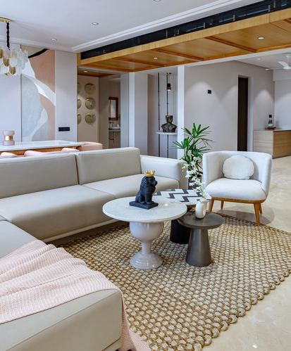 Nude-toned living room with sectional sofa, layered round coffee tables and wood-clad ceiling detail