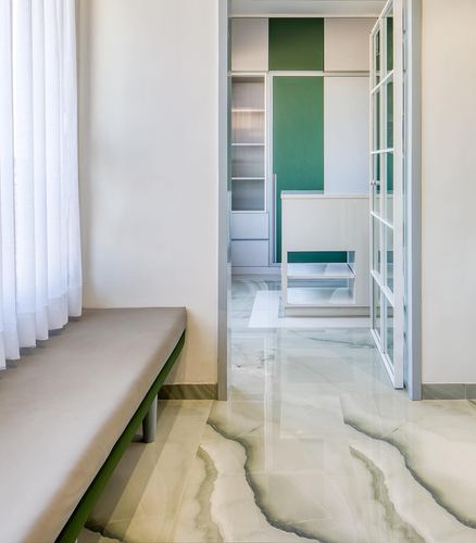 Marble-floored passage with green paneled wall visible through open glass door, bench beside sheer curtain