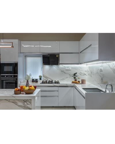 White gloss modular kitchen with marble-look counters, island, and built-in oven
