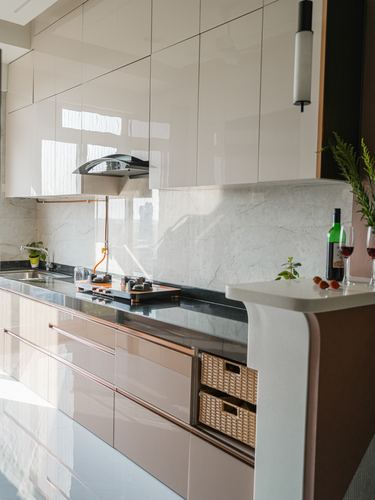 Glossy beige and blush kitchen cabinetry with marble backsplash and rounded white counter edge