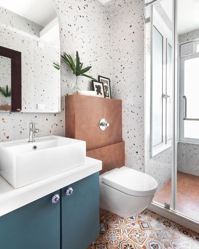 Bathroom with terrazzo walls, teal vanity, wall-hung toilet, and patterned floor tiles