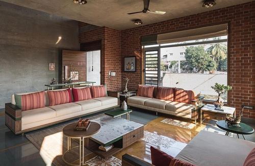 Sunlit living room with brick walls, beige sofas, striped cushions and brass-framed tables