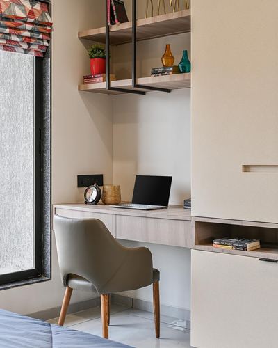 Small study nook with floating wood desk, leather chair, and suspended shelf unit beside window