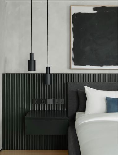 Dark fluted wood nightstand and headboard wall beneath two black pendant lights and abstract art