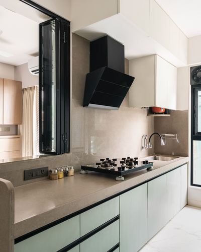 Modern galley kitchen with black chimney hood, stone counter, and sage green cabinetry