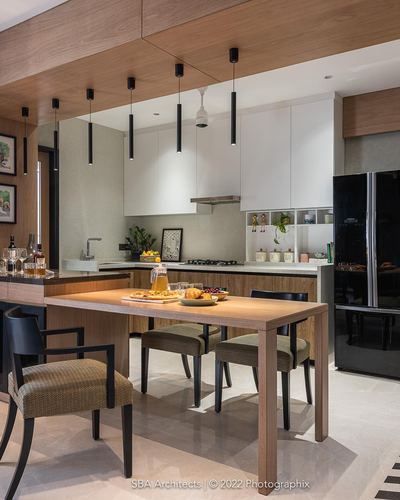 Modern kitchen and dining nook with wooden table, black pendant lights, and white cabinetry