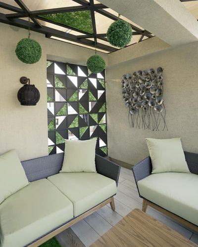 Terrace lounge with wicker sofas, sage cushions, geometric metal screen and sculptural wall art
