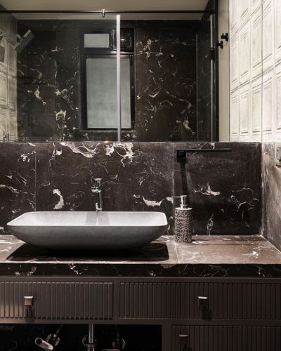 Dark veined stone bathroom vanity with grey vessel sink and fluted wood cabinetry