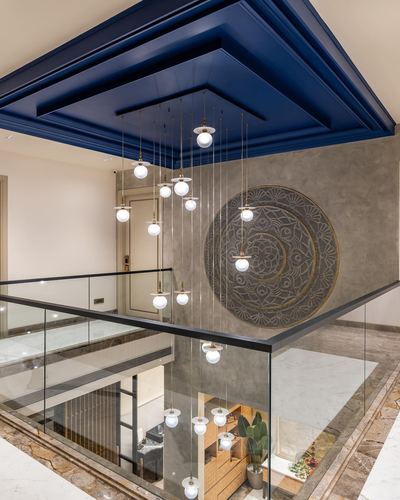Double-height foyer with navy coffered ceiling, cascading globe pendants, and carved circular wall panel