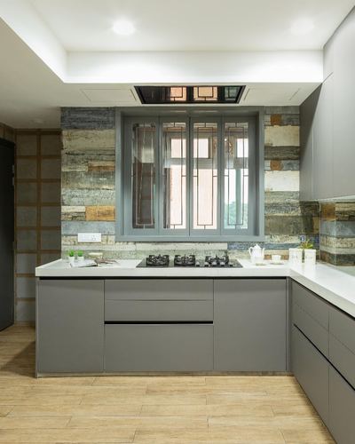 Grey modular kitchen with textured stone backsplash and patterned window above cooktop