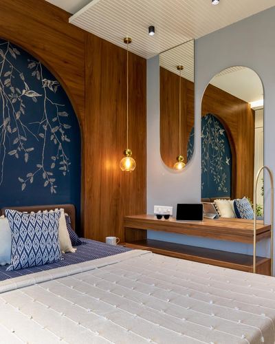 Bedroom with wood-panelled arched niches, blue floral mural, brass pendant lights, and floating wooden console.