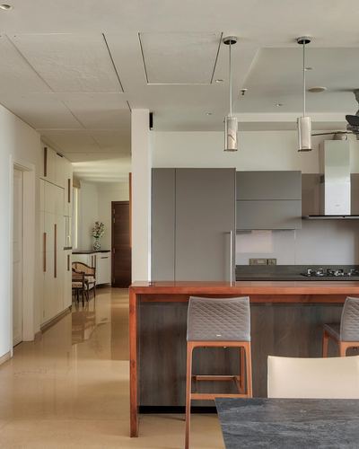 Minimalist kitchen with grey cabinetry, wood-topped island, and view down a long corridor