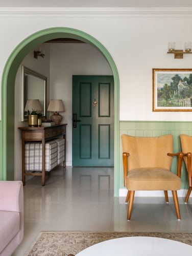 Living room with arched green doorway opening to entrance foyer with green door and console table