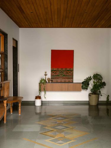 Foyer with wood-panelled ceiling, red textile art above a wooden console, and inlaid terrazzo floor pattern