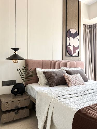 Bedroom with pink ribbed headboard, patterned pillows, wood bedside table, and cone pendant light