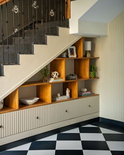 Under-stair storage nook with wooden cubbies, ribbed cabinets, and black-white checkerboard floor