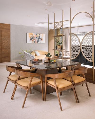 Dining room with marble table, wood chairs, and circular jali partition dividing living space