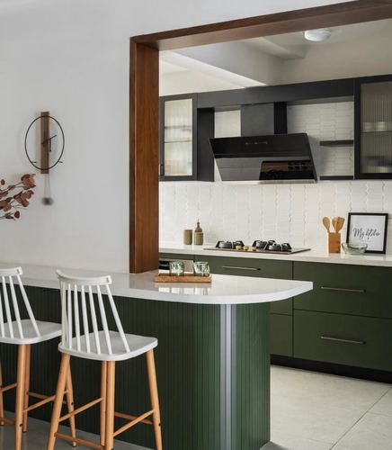 Green and white modern kitchen with black chimney hood and curved island counter
