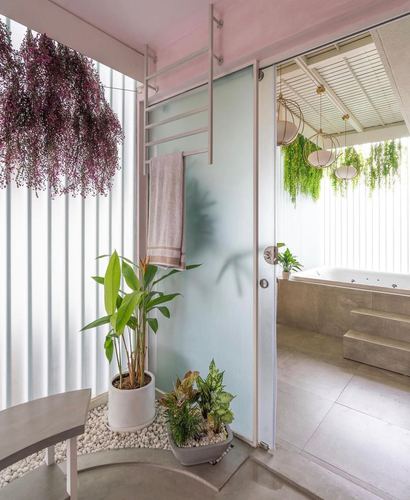 Bathroom with frosted sliding door, pebble planter bed, and sunken tub beyond, lit by soft daylight