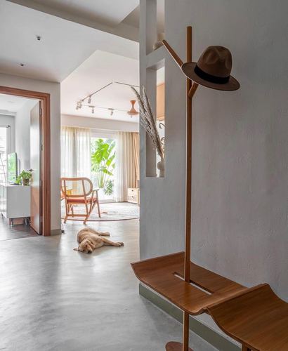 Entry hallway with wooden coat rack holding a hat, dog sleeping near living room beyond