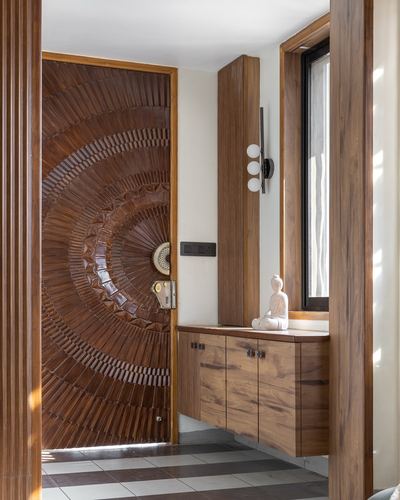 Entry foyer with radially carved wooden door and floating wood cabinet beneath a window