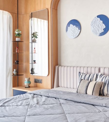 Bedroom corner with curved wood panelling, mirror, display shelves, striped headboard and blue circular wall art