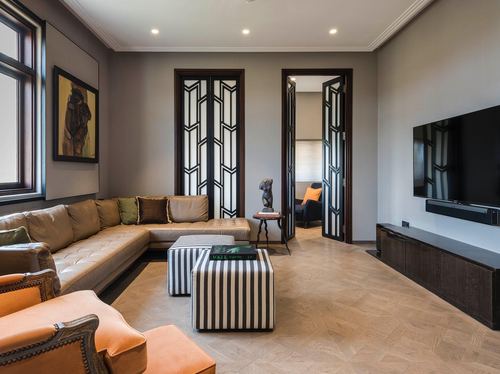 Art deco living room with leather sectional, striped ottomans, and fluted glass doors in Mumbai apartment